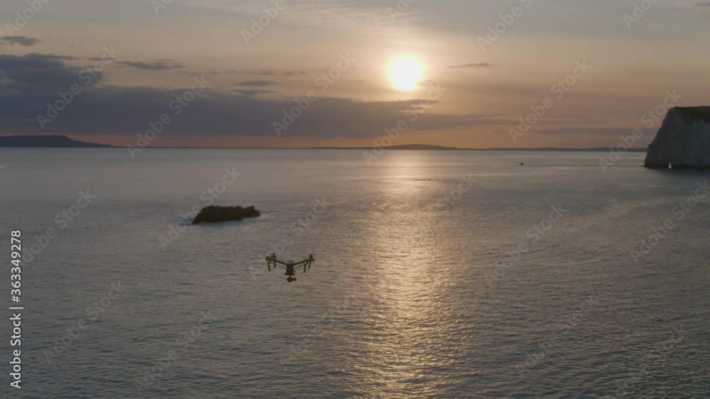 Aerial drone air to air shot circling around a DJI Inspire 1 drone in flight hovering over the sea at sunset