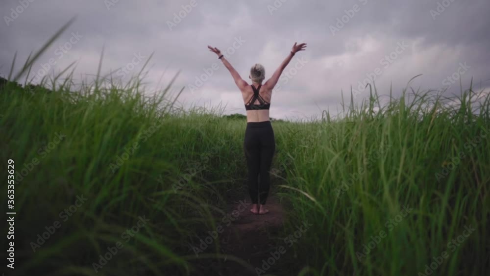 Young woman practice yoga outdoor in rice fields in the evening during wellness retreat in Bali. Slow Motion Rapid Young woman practice yoga outdoor in rice fields in the evening during wellness retreat in Bali. Slow Motion Rapid