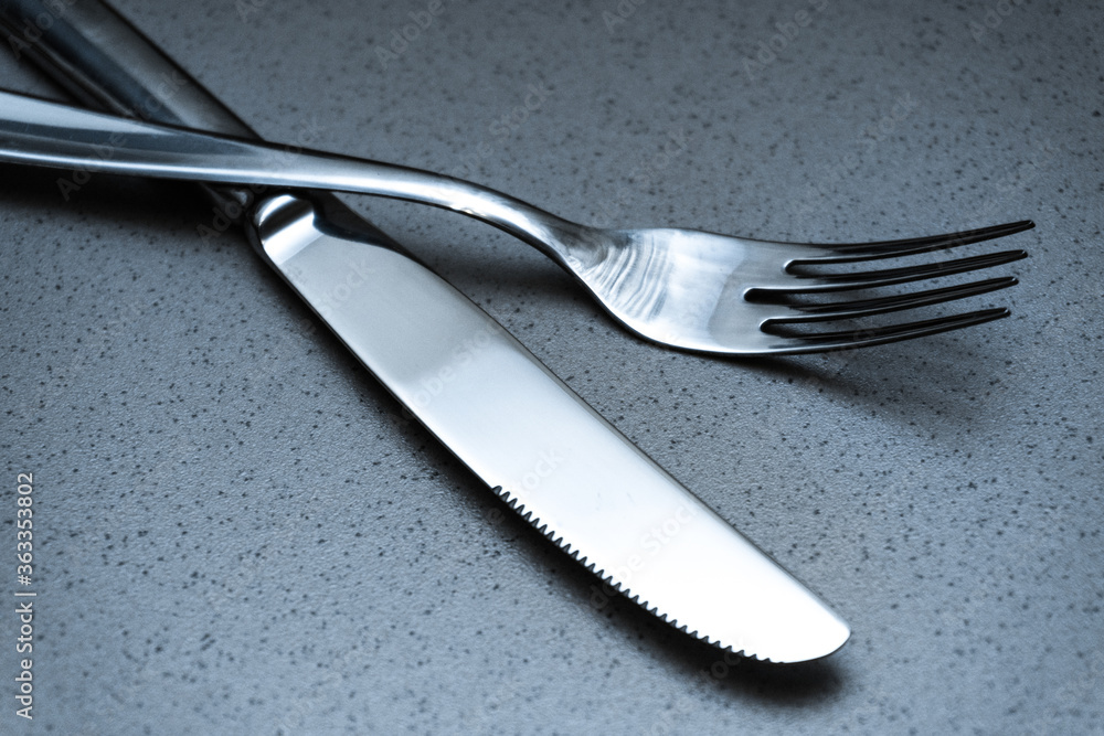 Kitchen utensils, fork and knife on a stone countertop Kitchen utensils, fork and knife on a stone countertop