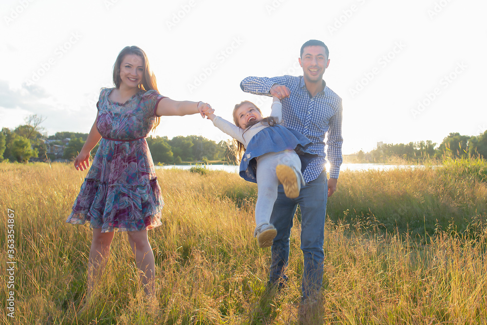 Happy young family walks in nature, at sunset Happy young family walks in nature, at sunset