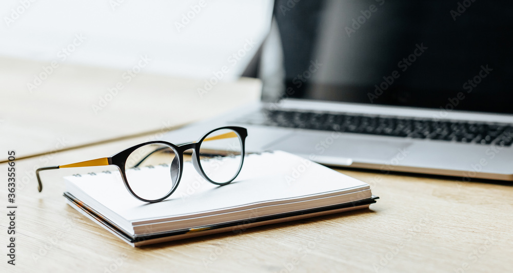 Glasses at the workplace in the office near the laptop and notepad. Business hours Glasses at the workplace in the office near the laptop and notepad. Business hours