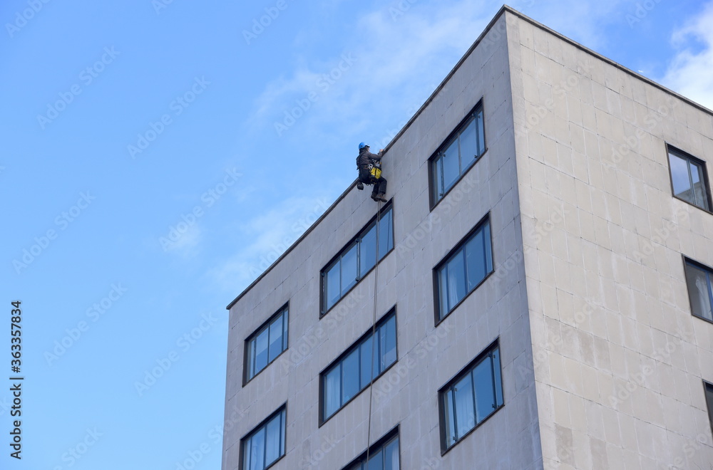 Bauarbeiter beim Abseilen an der Fassade eines Hochhauses 