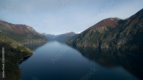 Aerial view of a pure blue water lake, the cliffs, forest mountains and the reflection in the water surface. 
