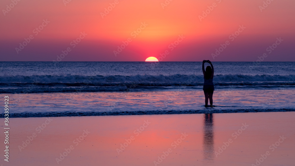 Girl takes a photo of the sunset on the beach