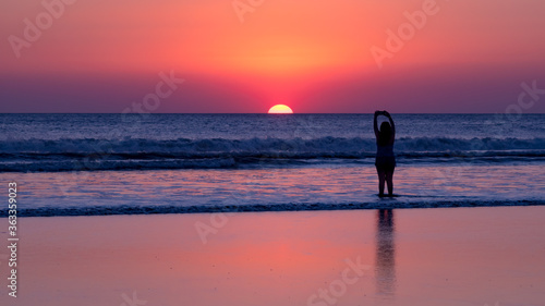 Girl takes a photo of the sunset on the beach