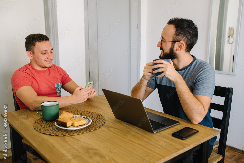 Two men sitting using laptop and phone. Two men sitting using laptop and phone.
