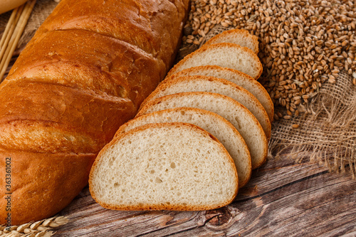 Obraz na płótnie Close-up of homemade bread. Peasant loaf bread and wheat spikelets with space for text. Homemade baking. White bread with flour and milk on wooden chopping board wheat rye ears copy space. w salonie