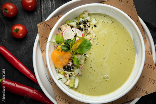 Top view of traditional Russian summer kefir or yogurt cold soup with vegetables called Okroshka. on a dark background
