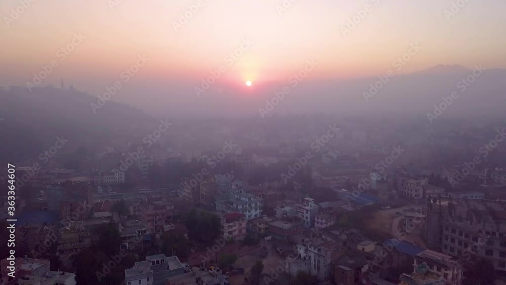 Aerial drone shot flying backwards over Kathmandu, Nepal at sunrise on a mist hazy morning, with smoke rising from the houses below Aerial drone shot flying backwards over Kathmandu, Nepal at sunrise on a mist hazy morning, with smoke rising from the houses below