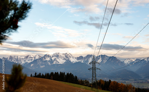 sunrise in the austrian alps in late spring with snow and dew on the field and power supply line