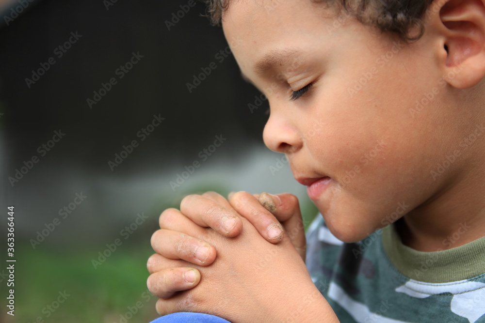 boy praying to God with hands together and closed eyes stock photo boy praying to God with hands together and closed eyes stock photo