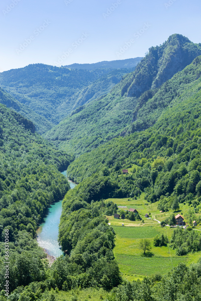Top view of the mountain river Tara and mountains covered by coniferous forest, the village is located in the gorge, Montenegro, Europe. Top view of the mountain river Tara and mountains covered by coniferous forest, the village is located in the gorge, Montenegro, Europe.