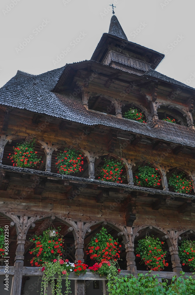 Barsana Monastery, Maramures, Romania, Europe, Summer 2018. Wooden building with red geraniums hanging from the windows of the Barsana Orthodox Monastery.