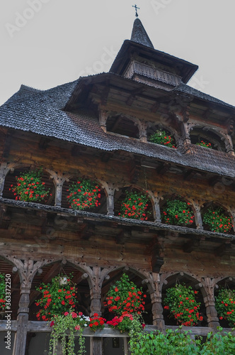 Obraz na płótnie Barsana Monastery, Maramures, Romania, Europe, Summer 2018. Wooden building with red geraniums hanging from the windows of the Barsana Orthodox Monastery. w salonie