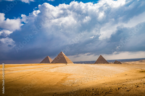 Wide landscape shot of Giza pryamids with dramatic clouds and light