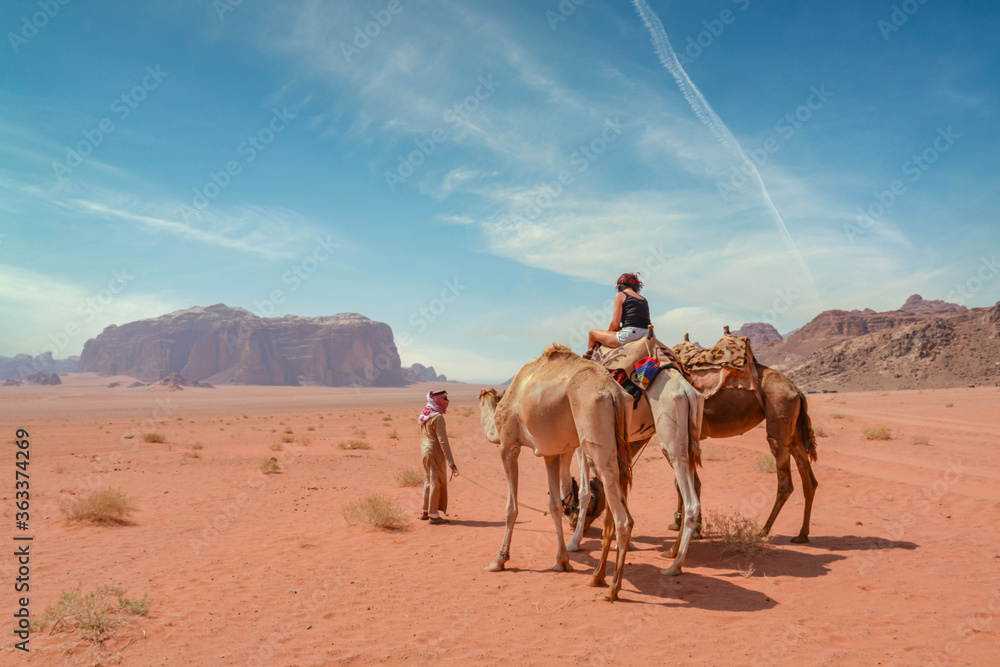 Fototapeta premium Female tourist riding a camel in the Wadi Rum desert 
