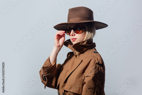 Style woman in cloak, hat and sunglasses on grey background