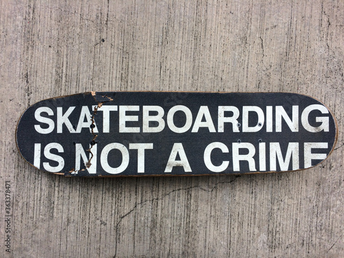 Broken Skateboard that reads on its Grip-tape "Skateboarding is not a Crime"