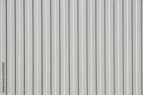Gray corrugated metal fence on a sunny day..Corrugated surface seamless pattern.