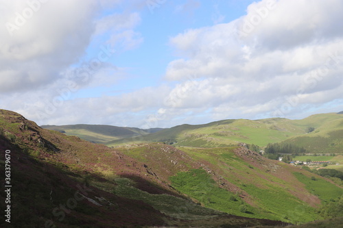 Green rolling hills and fields with blue sky and clouds