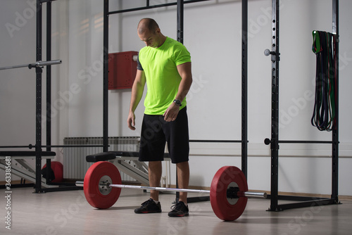 Trainer In The Gym Exercising Back With Barbell