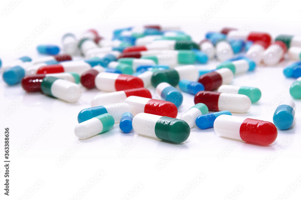 Medical pills in red, blue, green and other colors. Loose tablets on white surface. Health and medicine