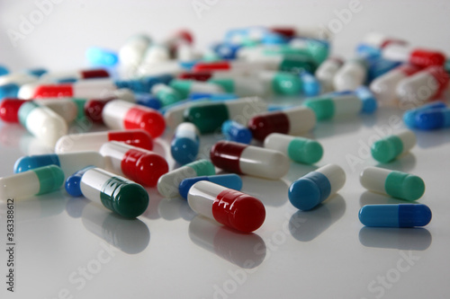 Medical pills in red, blue, green and other colors. Loose tablets on white surface. Health and medicine