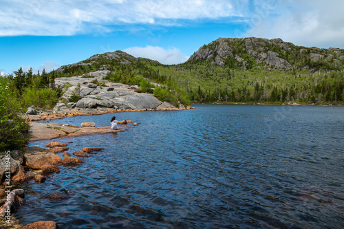 A woman taking in a serene setting at a mountain lake. 