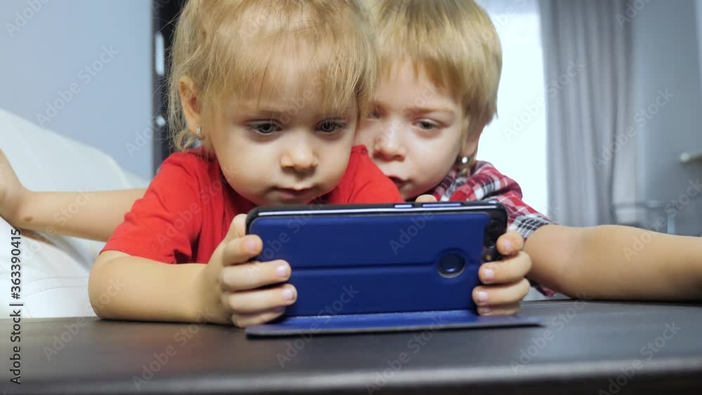 children watch online video on a smartphone. little boy and girl lifestyle brother sister watch online streaming broadcasting cartoons on the phone children watch online video on a smartphone. little boy and girl lifestyle brother sister watch online streaming broadcasting cartoons on the phone