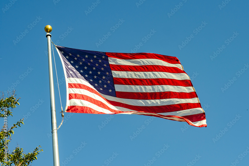Obraz premium American flag waving in the wind against blue sky, California