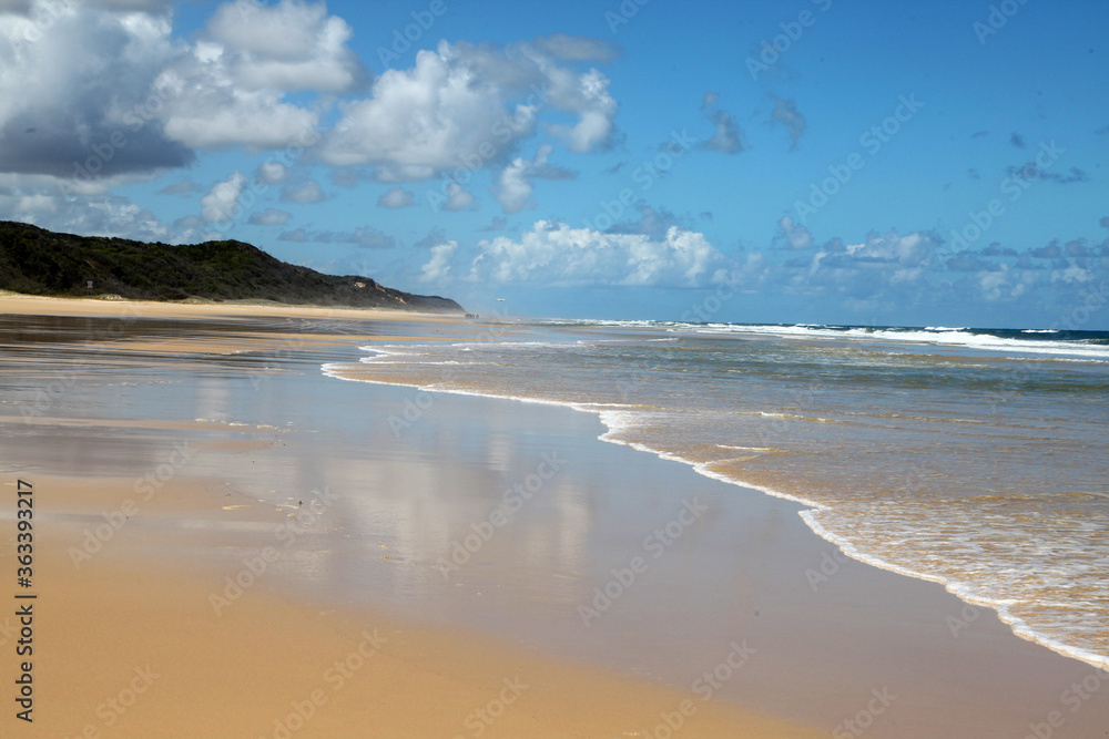 Beautiful image of Fraser Island along 75 miles beach showing blue sky, sand, water and waves