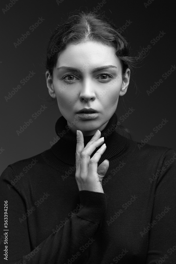 Fototapeta premium Attractive brunette girl in a dark sweater poses for the camera. black and white image