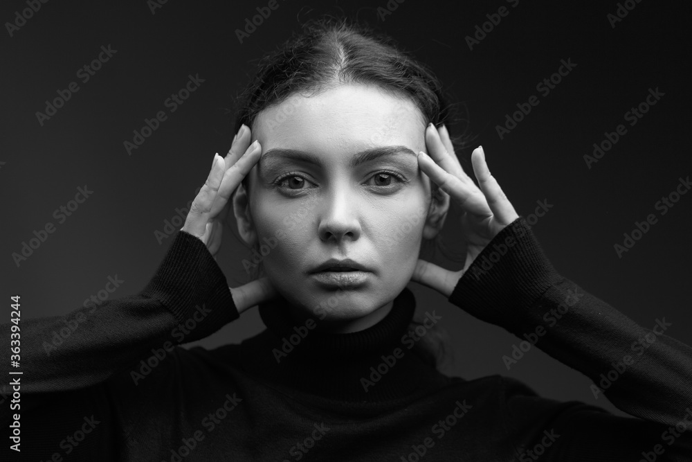 Attractive brunette girl in a dark sweater poses for the camera. black and white image Attractive brunette girl in a dark sweater poses for the camera. black and white image