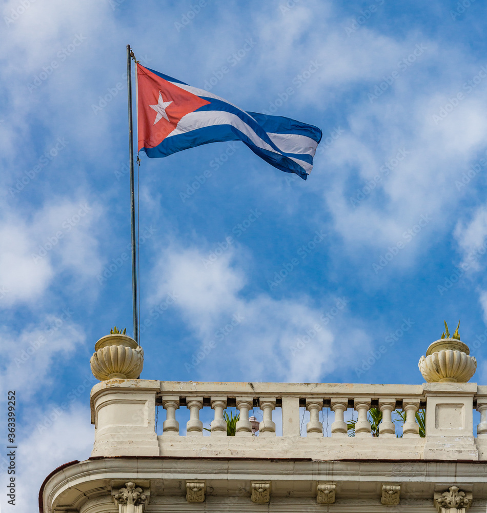 Cuban flag of red, white and blue, flies on top of building in Havana, Cuba