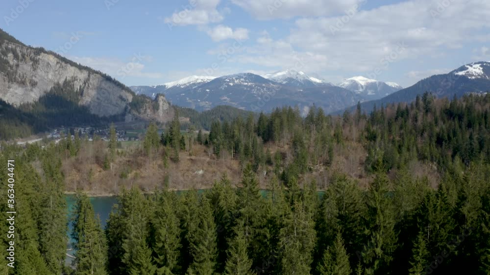 Aerial drone shot gliding over beautiful hidden lake and pine forest in Switzerland with alps in the background Aerial drone shot gliding over beautiful hidden lake and pine forest in Switzerland with alps in the background