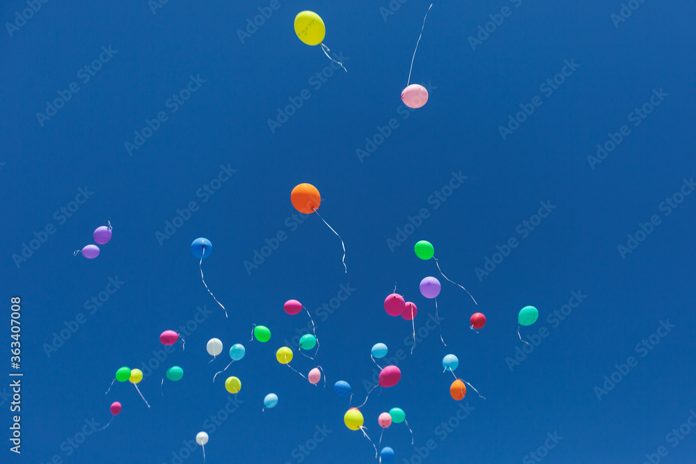 Multicolored flying balloons directed to the blue sky during party celebration Multicolored flying balloons directed to the blue sky during party celebration