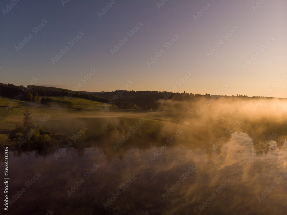 Sunset or dawn on a morning lake or swamp, steam and haze