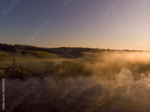 Sunset or dawn on a morning lake or swamp, steam and haze