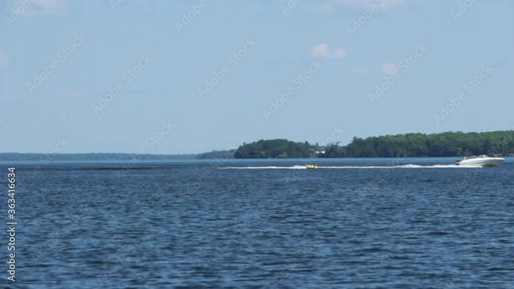 White Speedboat Sailing On The Beautiful Kawartha Lakes On A Bright Weather In Ontario, Canada. - wide shot White Speedboat Sailing On The Beautiful Kawartha Lakes On A Bright Weather In Ontario, Canada. - wide shot