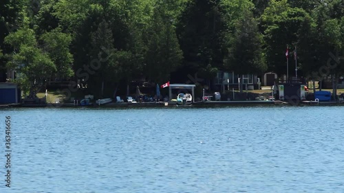 Waterfront Houses And Harbor Surrounded By Green Trees By The Kawartha Lakes In Ontario, Canada On A Sunny Day. -wide shot photo