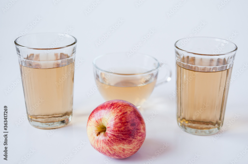 A mug and glass of Apple juice and a red Apple on a white background A mug and glass of Apple juice and a red Apple on a white background