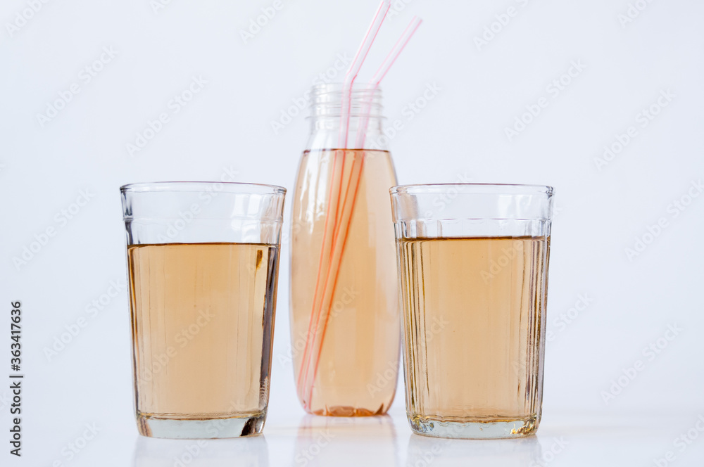 Two glasses and a bottle with Apple juice tubes on a white background Two glasses and a bottle with Apple juice tubes on a white background
