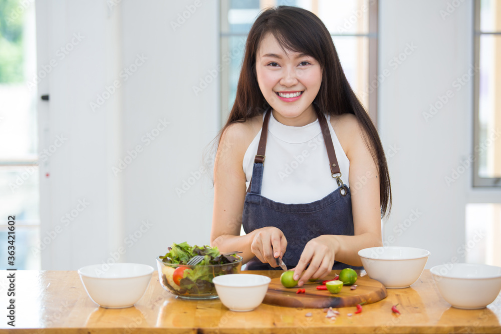 Beautiful Asian women, beautiful smile, good health, beautiful teeth, eating salad vegetable when working at home.