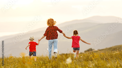 Happy woman with kids running back in field.
