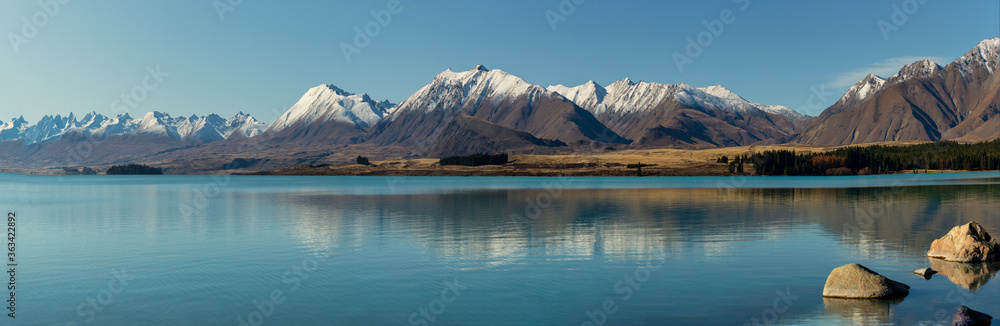 The beautiful still waters  of Lake Tekapo reflecting the snow capped Southern Alps in New Zealand