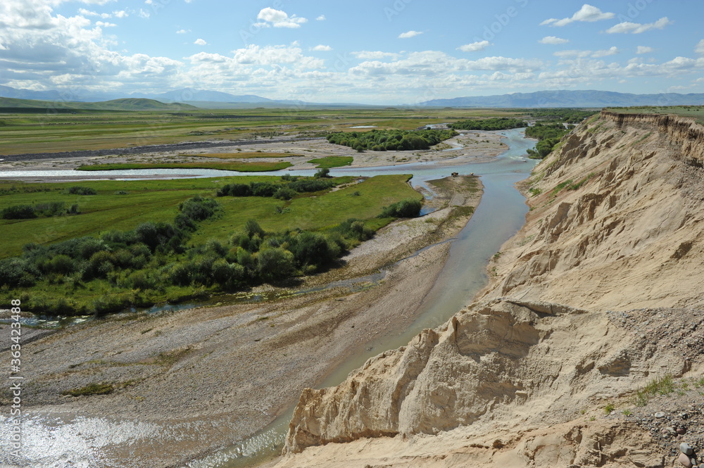 A valley with a mountain river and grazing animals. Territory near the Khan Tengri mountain range. A valley with a mountain river and grazing animals. Territory near the Khan Tengri mountain range.