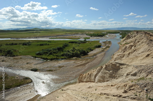 A valley with a mountain river and grazing animals. Territory near the Khan Tengri mountain range.