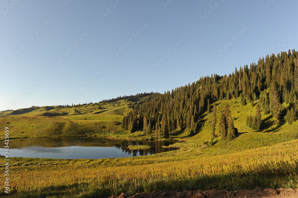 Flood of the river in a wide valley against the background of hills with different vegetation. Sunset time of day.