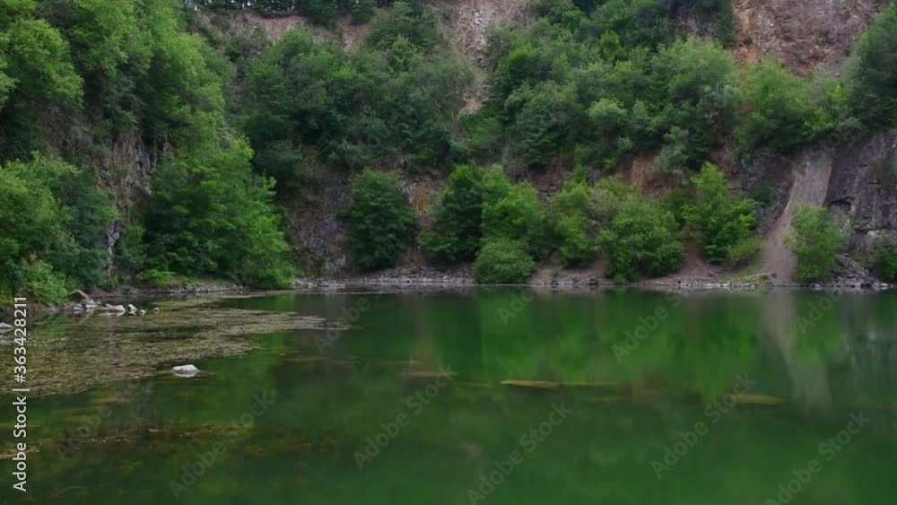 Static view of beautiful green lake with clear water and erosion rock formation in background, summer day. Static view of beautiful green lake with clear water and erosion rock formation in background, summer day.