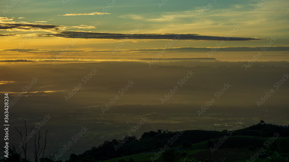 View of landscape with light sunrise on the horizon in the valley. Bright sky over mist mountains. Concept of nature. Tourist attraction Phu Thap Berk, Phetchabun, Thailand